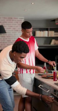 Dikey video: çeşitli erkek arkadaşlar omuz vuruyor, pizza birleştiriyor ve mutfakta soda paylaşıyorlar. İşbirliği, aşçılık, modern, ev, eğlence, yaşam tarzı, dikey video