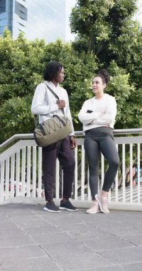 Dikey video: Köprüdeki çeşitli arkadaşlara yaklaşıyoruz. Duffel 'i ayarlıyorlar ve selamlama için beşlik çakıyorlar. Kentsel, sosyal, gündelik, yaşam tarzı, canlı, arkadaşlık, dikey video