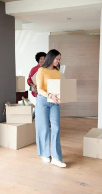 Dikey video: Çeşitli çiftler ahşap kapıdan girip kutuları yerleştiriyor ve eşyaları boşaltıyorlar. Taşınma, taşınma, yeni taşınma, yeni ev, ev, organizasyon, dikey video