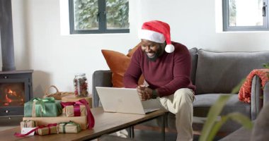 İhbar geliyor, Afrika kökenli Amerikalı adam Noel Baba şapkası takıyor, el çırpıyor ve dizüstü bilgisayarını işaret ediyor, kaşlarını çatıyor. Şenlik, kutlama, ev, konfor, iş, gündelik, sıcaklık