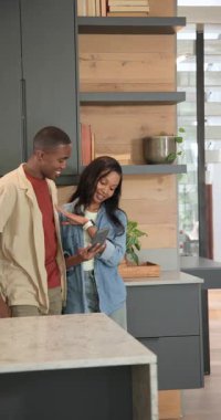 Dikey video: Akıllı telefon listesindeki Afro-Amerikan çiftin adada paketleri boşaltması. Çift, ev, mutfak, teknoloji, gündelik, modern, dikey video