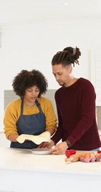 Dikey video: Mutfak adasında hamuru yuvarladıktan sonra, çiftler turta için turta tavasına hamur kabuğu sıkıştırıyorlar. Aile içi, işbirliği, aşçılık, yaşam tarzı, kırsal, hareketli, dikey video