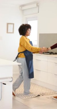 Dikey video: Çeşitli çiftler birbirlerini davet ediyor, mutfak tezgahının yanında dans ediyorlar. Romantizm, samimiyet, hareket, neşe, yerli, modern, dikey video