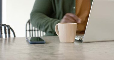 Evde dizüstü bilgisayarda yazan Afro-Amerikalı bir adam. Sonra telefonları durdurup gülümsüyor ve arıyor. Profesyonel, evden çalışma, modern, rahat, iletişim, teknoloji, yaşam tarzı