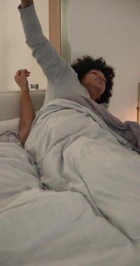 Dikey video: Alarm saatine tepki veren iki adam çalar, kapanır, yatakta sarılır, uzaktan kumanda kullanır. Romantizm, samimiyet, şefkat, şafak, evcil, konfor, dikey video