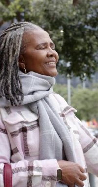 Dikey video: Kıdemli Afro-Amerikan kadın hareketini fark ediyor ve kafasını çantasıyla yola koyuyor. Kentsel, doğa, zarafet, farkındalık, yansıma, sakin, dikey video