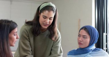 Çeşitli bayan meslektaşlar ellerinde bardak tutarken tablet üzerinde proje sunarak konuşuyorlar. İşbirliği, takım çalışması, yenilik, modern, kurumsal, iletişim, çeşitlilik