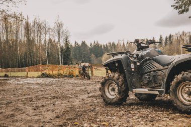 Ön planda çamurda dört tekerli bisiklet ve bir motosiklet. Ekstrem moto sporları.