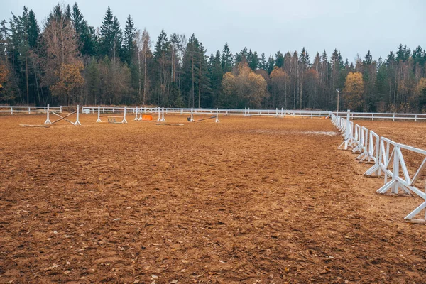 Pure white racetrack against the backdrop of a beautiful autumn forest. White fence in the background of nature.