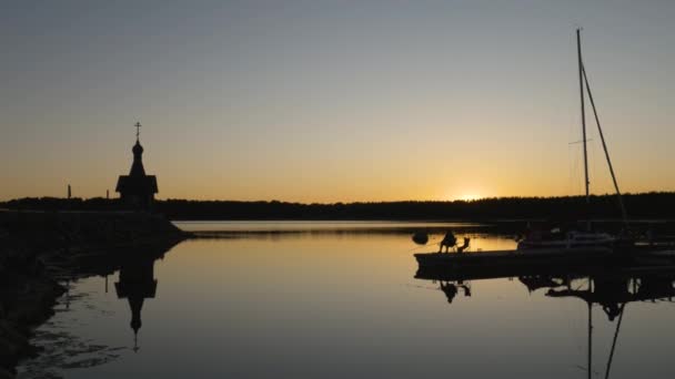 Fisherman Sits Wharf Fishes Sunset Silhouette Fisherman Church Quiet Lake — Stock Video