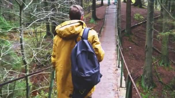 Man Yellow Jacket Backpack Walks Suspension Bridge View Tourist Forest — Stock Video