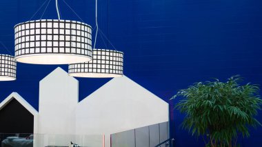 Parlak mavi bir duvar, ve önünde 3 yuvarlak lamba ve bir bitki ile bir çalı.