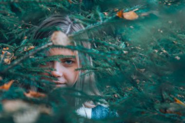 Bir kız ormanda dolaşır, Noel ağacının altından çıkar, bir yol arar. Ormandaki yeşilliklerin arasından kızın bakışları.