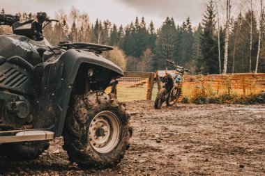 Ön planda çamurda dört tekerli bisiklet ve bir motosiklet. Ekstrem moto sporları.
