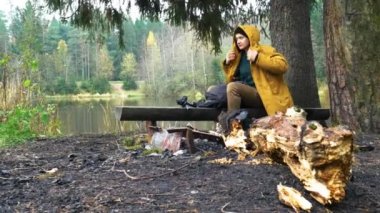 Bir adam gölün kenarında bankta oturuyor. Ağacın yanında. Göl kenarında fotoğrafçı. Sakin, hayat hakkında fikir yürüten.
