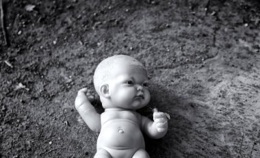 Çöpte terk edilmiş plastik bebek, unutulmuş oyuncaklar, bölünmüş masumiyet.