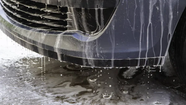 Washing car with hose and soap, mechanical workshop, vehicle maintenance