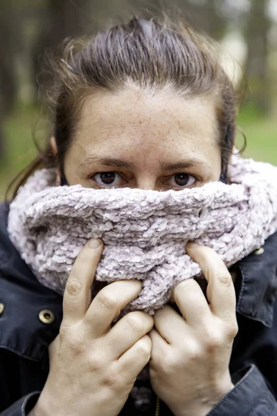 Woman with scarf and cold tabpada in forest, inclement weather