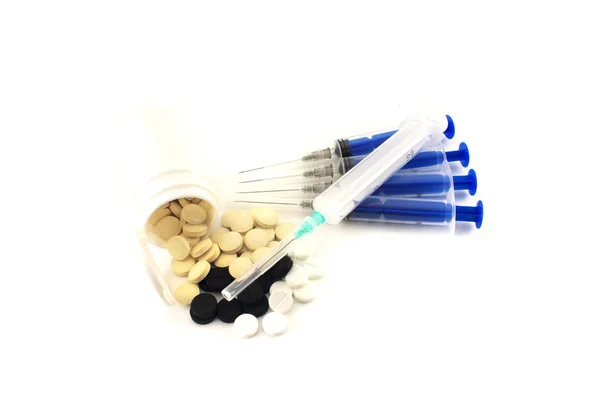 A handful of scattered tablets surrounded by syringes. Isolated — Stock Photo, Image