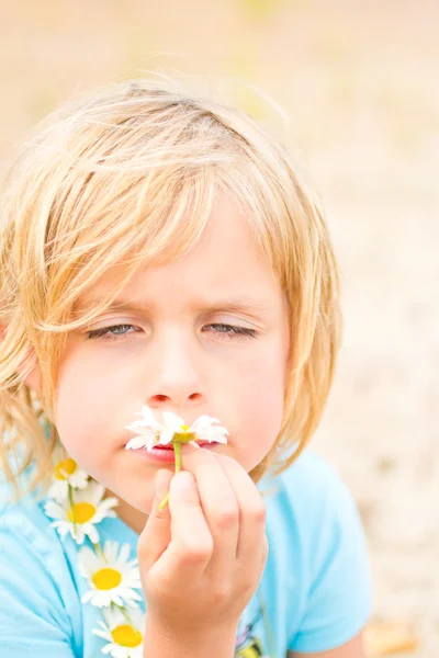 Dummes kleines blondes Mädchen, das ein Gänseblümchen riecht — Stockfoto