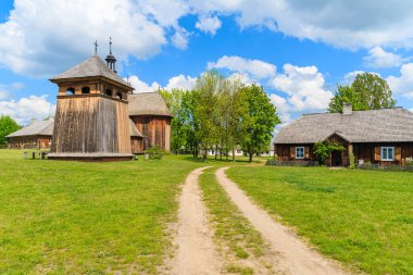 Tokarnia köyünde kırsal yol güneşli bahar gününde eski ahşap kilise, Polonya