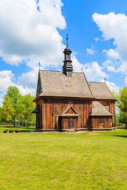 Tokarnia köyündeki yeşil çayır üzerindeki eski ahşap kilise güneşli bahar gününde, Polonya