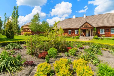 TOKARNIA VILLAGE, POLAND - 12 Mayıs 2016: Tokarnia köyündeki eski malikane evinin önündeki çiçek bahçesi güneşli bahar günü, Polonya.