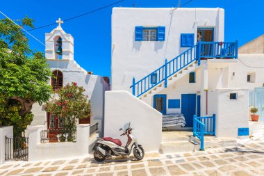 MYKONOS TOWN, GREECE - 16 Mayıs 2016: Scooter Yunanistan 'ın Mykonos adasındaki tipik bir Yunan evi ve kilisesinin önündeki sokağa park etti.