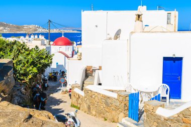 Yunanistan 'ın güzel Mykonos kasabası Cyclades adalarındaki mavi kapısı ve kilisesi olan tipik beyaz bir Yunan evi.