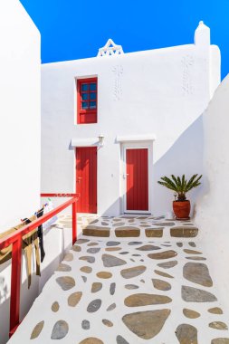 Yunanistan 'ın güzel Mykonos kasabası Cyclades adalarında kırmızı kapıları ve penceresi olan tipik beyaz bir Yunan evi