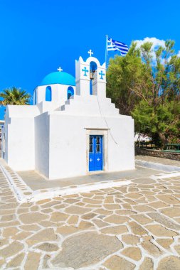 Paros Adası, Kiklad, Yunanistan 'da mavi kubbeli ve Yunan bayrağıyla tipik beyaz kilisesi olan meydan