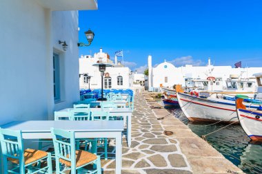 Taverna masaları ve Naoussa limanı, Paros adası, Kiklad, Yunanistan 'daki tipik Yunan balıkçı tekneleri