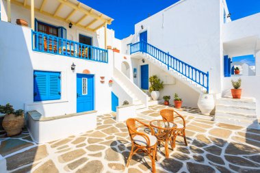 NAOUSSA TOWN, PAROS ISLAND - 19 Mayıs 2016: Yunanistan 'ın Paros Adası' ndaki Naoussa kasabasındaki tipik Yunan tarzı apartman kompleksinin avlusunda sandalyeli masa.