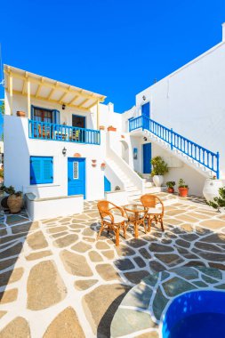 NAOUSSA TOWN, PAROS ISLAND - 19 Mayıs 2016: Yunanistan 'ın Paros Adası' ndaki Naoussa kasabasındaki tipik Yunan tarzı apartman kompleksinin avlusunda sandalyeli masa.