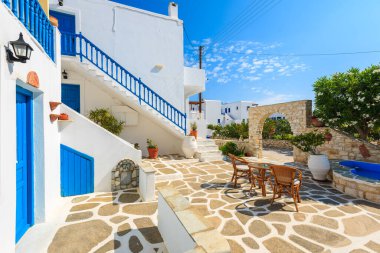 NAOUSSA TOWN, PAROS ISLAND - 19 Mayıs 2016: Yunanistan 'ın Paros Adası' ndaki Naoussa kasabasındaki tipik Yunan tarzı apartman kompleksinin avlusunda sandalyeli masa.