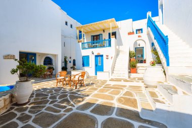 NAOUSSA TOWN, PAROS ISLAND - 19 Mayıs 2016: Yunanistan 'ın Paros Adası' ndaki Naoussa kasabasındaki tipik Yunan tarzı apartman kompleksinin avlusunda sandalyeli masa.