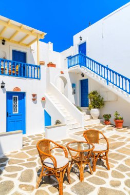 NAOUSSA VILLAGE, PAROS ISLAND - 18 Mayıs 2016: Yunanistan 'ın Paros Adası' ndaki Naoussa kasabasında güzel Yunan tarzı tatil dairelerinin avlusunda sandalyeli masa.