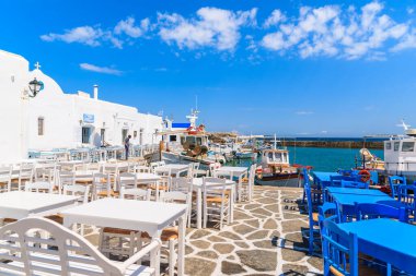 NAOUSSA PORT, PAROS ISLAND - 20 Mayıs 2016: Naoussa limanı, Paros adası, Kiklad, Yunanistan 'daki taverna masaları ve tipik beyaz Yunan binaları.