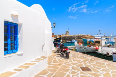 NAOUSSA PORT, PAROS ISLAND - 20 Mayıs 2016: Naoussa limanı, Paros adası, Kiklad, Yunanistan 'daki tipik beyaz Yunan kilisesinin önüne park eden scooterlar.