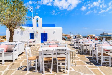 Naoussa limanı, Paros adası, Kiklad, Yunanistan 'da tipik beyaz Yunan kilisesi bulunan bir meydanda bar masaları