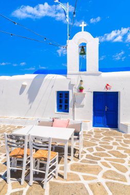Naoussa limanı, Paros adası, Kiklad, Yunanistan 'daki tipik beyaz Yunan kilisesinin önündeki bar masaları