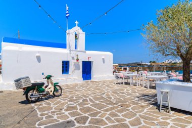 PAROS ISLAND, GREECE - 20 Mayıs 2016: Yunanistan 'ın Paros Adası' ndaki Naoussa limanındaki bir kilisenin önündeki klasik eski scooter park yeri.