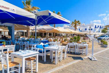 PAROS ISLAND, GREECE - 20 Mayıs 2016: Naoussa limanı, Paros Adası, Yunanistan 'da turistleri bekleyen restoran masaları.