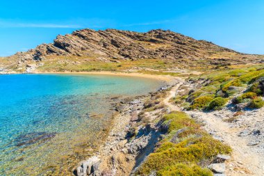 Yunanistan 'ın Paros adasındaki Monastiri körfezinde kristal berrak deniz suyu boyunca uzanan güzel kıyı yolu