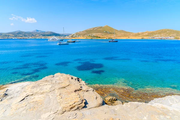 Paros adası kıyılarında kayalar ve gök mavisi deniz suyunda yelkenli kayıklar, Yunanistan