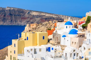 OIA VILLAGE, SANTORINI Adası- 23 Mayıs 2016: Mavi kubbeli beyaz kiliseleriyle tanınan ünlü Oia köyündeki renkli evler, Yunanistan 'ın Santorini adası.