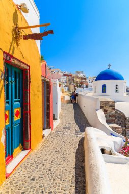 Yunanistan 'ın Santorini adasındaki Oia köyünde renkli evi ve kilisesi olan dar bir sokak.