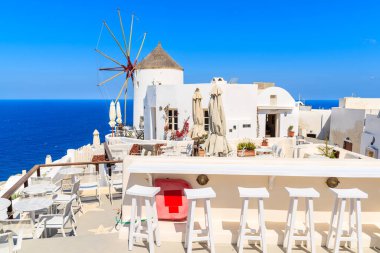 OIA, SANTORINI ADLAND - 23 Mayıs 2016: Yunanistan 'ın Santorini adasındaki Oia köyünde restoran ve ünlü yel değirmeni.