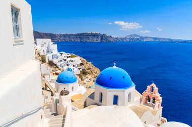 Oia köyündeki ünlü mavi kubbe ve Yunanistan 'ın Santorini adasındaki kalderalı mavi deniz manzarası.