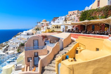 OIA TOWN, SANTORINI ISLAND - 23 Mayıs 2016: Yunanistan 'ın Santorini adasındaki Oia kasabasında turistlerle dolu renkli evler ve restoran terası.